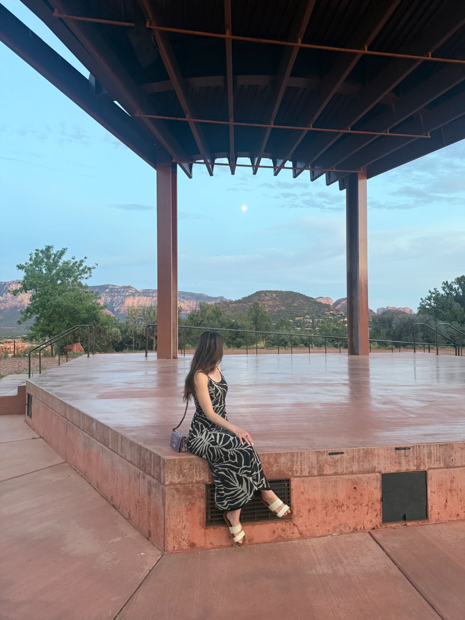 Jacquelyn seated beneath the moon with the Sedona landscape beyond