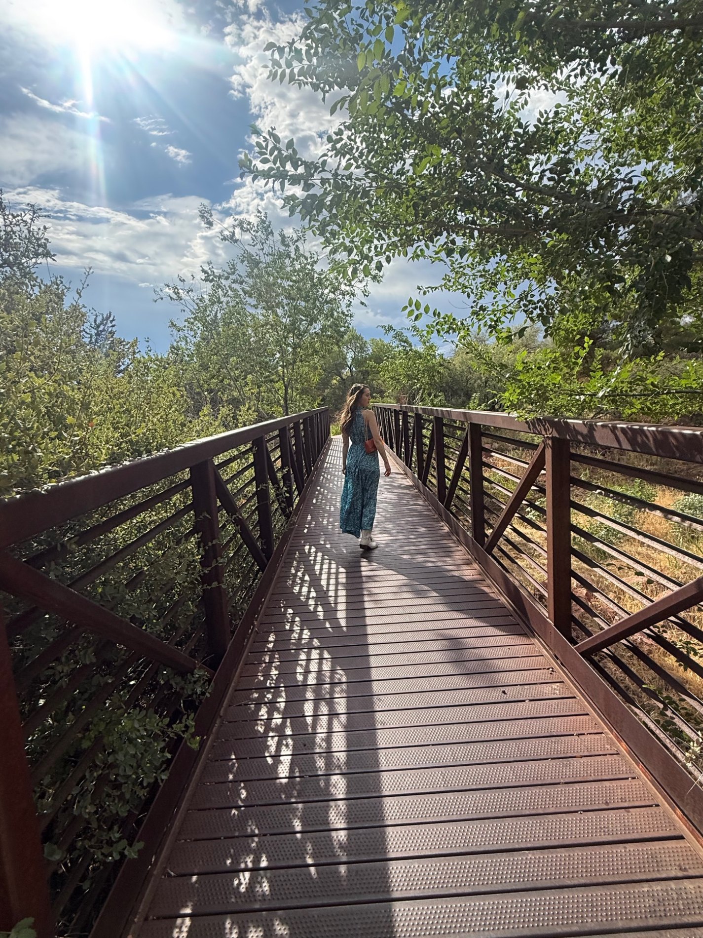 Jacquelyn walking across a sunlit bridge in Sedona